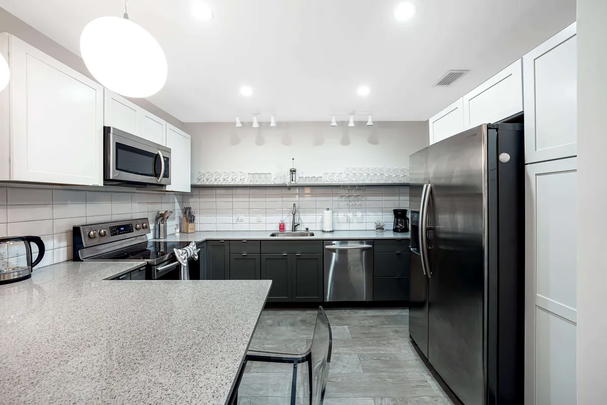 A bright, functional kitchen with granite countertops, stainless steel appliances, and elegant hanging lights. The space feels warm and inviting, perfect for family breakfasts or preparing festive dinners. Kitchen tools and cookware are accessible, suggesting a space ready for cooking and gathering.