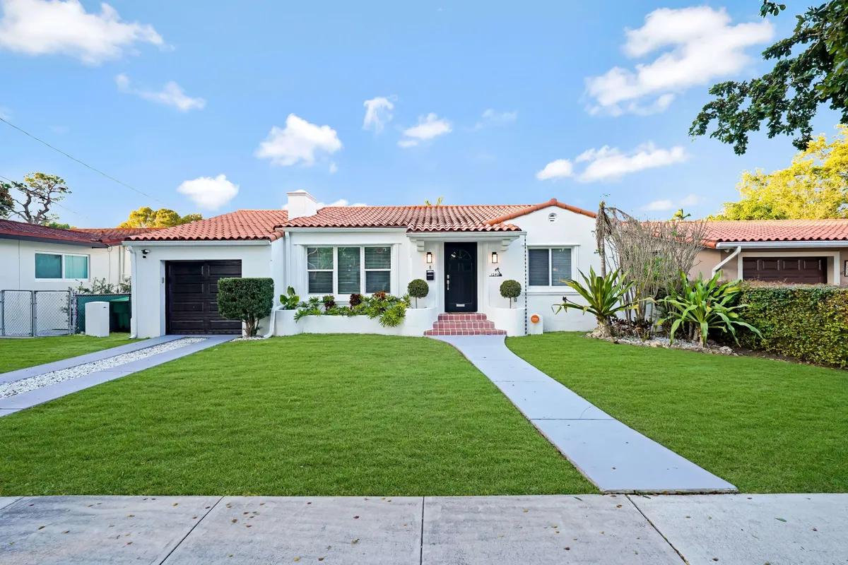 This image features the home's welcoming front door framed by a beautifully landscaped lawn and a clear, inviting pathway. The scene exudes a sense of arrival and first impressions, setting the tone for both relaxing downtime and productive days. Lush greenery hints at the vibrant outdoor life Miami offers.